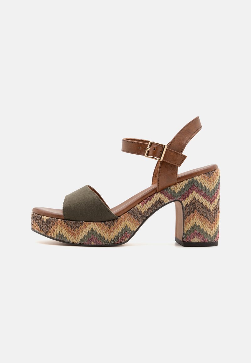 Sandale à chevilles en cuir brun avec un panneau avant vert olive, dotée d'un talon compensé texturé à motif zigzag dans des tons terreux.