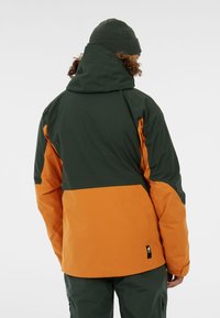 Kapuzenshirt in Dunkelgrün und Orange. Verfügt über ein Farbblock-Design mit einer strukturierten Oberfläche. Enthält ein kleines Logo am Saum.