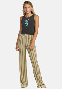 Top senza maniche nero con grafica turchese; pantaloni leggeri a righe beige con righe verticali verdi e gialle; vestibilità casual, tessuto morbido.