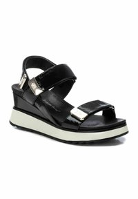 Sandalias de cuña de charol negro con dos correas ajustables, detalles metálicos y una suela blanca en contraste. Plantilla suave para mayor comodidad.