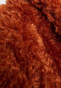 Rustfarvet, fluffet stof med en blød, tekstureret overflade, der har dyb luv og varierede længder for øget visuel interesse.