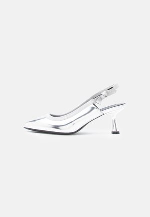 Srebrne czółenka typu slingback z zaostrzonym noskiem, średniowiecznym połyskującym obcasem i małą kokardką na pasku na jednolitym tle.