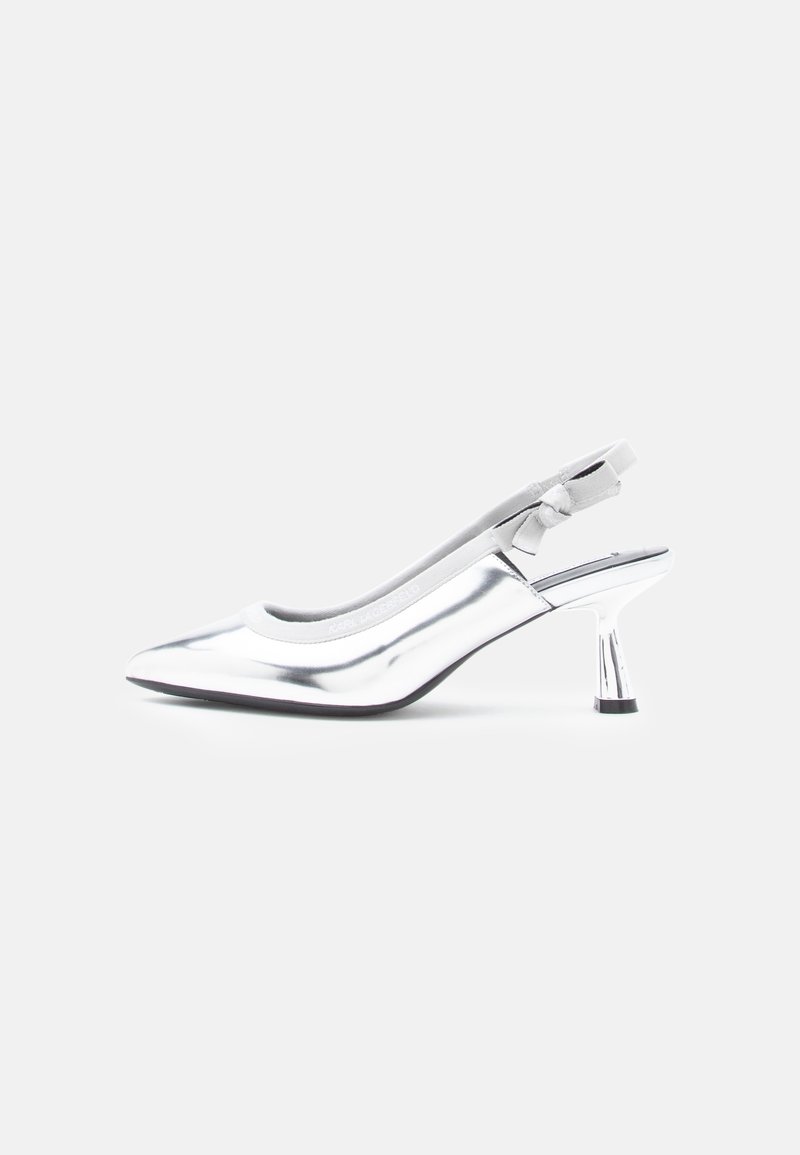 Chaussure slingback argentée à bout pointu avec talon moyen brillant et petit détail de nœud sur la bride sur fond uni.