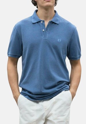 Camisa polo de tela azul suave, con cuello, tapeta de tres botones y un pequeño logotipo en el pecho. Ajuste casual y mangas cortas.