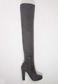 Botas negras de ante sobre la rodilla con una textura suave, tacón alto de bloque y detalle de cremallera lateral. Diseño elegante y ajustado para una silueta estilizada.