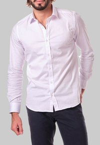 Chemise blanche à manches longues en tissu au toucher lisse, avec un col classique, une fermeture à boutons à l'avant et une coupe légèrement ajustée.