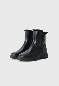 Zwarte leren enkellaarsjes met een ritssluiting, een gestructureerde voering aan de bovenkant en een dikke rubberen zool voor grip en stabiliteit.