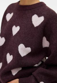 Maglione bordeaux con collo a giro, decorato con motivi a cuore rosa chiaro. Morbido al tatto, con polsini e orlo a coste.