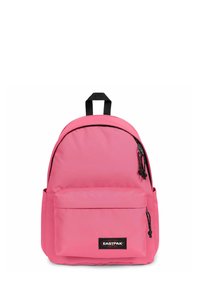 Mochila rosa hecha de tela con forma redondeada, que cuenta con un bolsillo frontal, detalles en cremallera negra y un asa superior para llevar.