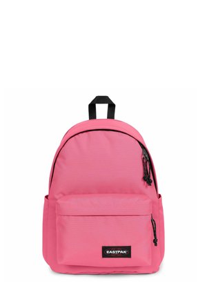 Mochila rosa hecha de tela con forma redondeada, que cuenta con un bolsillo frontal, detalles en cremallera negra y un asa superior para llevar.