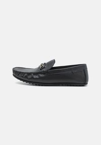 Schwarze Lederloafers mit runder Zehenpartie, einer dekorativen Schnalle und einer strukturierten Oberfläche. Verfügt über genähte Details entlang der Kanten.