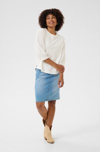 Cream blouse with embroidered, puffed sleeves; paired with a denim pencil skirt; model wears tan ankle boots. Clean, minimal design.