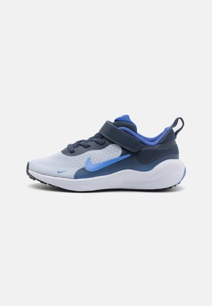 Baskets Nike avec une tige en mesh gris clair et marine. Un design en swoosh bleu, une sangle ajustable et une semelle en caoutchouc blanche.