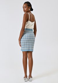 Gonna a maglia blu e bianco a quadri con vita a coste. Abbinata a un top in satin bianco e mocassini argentati.