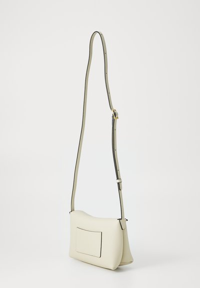 Krémová kožená crossbody taška s jemnou texturou, zakřiveným tvarem, nastavitelním popruhem a zadní kapsou. Kontrastní černý okrajový detail.