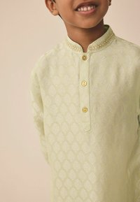 Helles grünes Kurta mit einem strukturierten Rautenmuster, goldenen Knöpfen und einer dekorativen Kragenapplikation vorne. Lange Ärmel und lockere Passform.