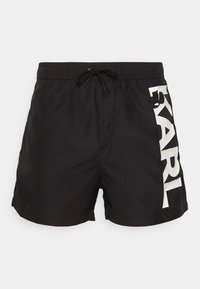 Juoda maudymosi šortai, pagaminti iš lengvos medžiagos, su elastingu juosmeniu ir raišteliu. Balta spalva „KARL“ logotipas atspausdintas šone.