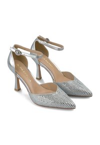 Scarpe con tacco alto argento con punta appuntita, caratterizzate da un frontale decorato con strass, cinturino alla caviglia e una finitura metallica strutturata.