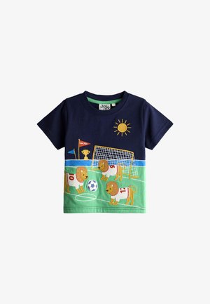 Marineblå og grøn toddlertrøje med løver, der spiller fodbold, et mål, en sol, en trofæ og flag på en fodboldbane baggrund.