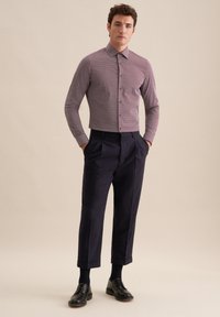 Koszula z kołnierzykiem i długim rękawem w małą kratkę w kolorze fioletowym i białym; zestawiona z spodniami o wysokim stanie w ciemnonawowym kolorze i czarnymi butami.