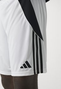 Hvite treningsshorts med svarte sidepaneler og tre svarte striper. Har adidas-logo i svart nær kanten. Laget av glatt, lettvektig stoff.