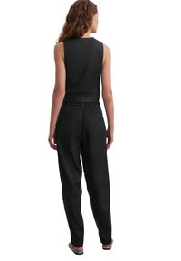 Tuta nera in lino con top senza maniche, scollo rotondo, vita elasticizzata e gambe affusolate. Design minimalista senza motivi visibili.