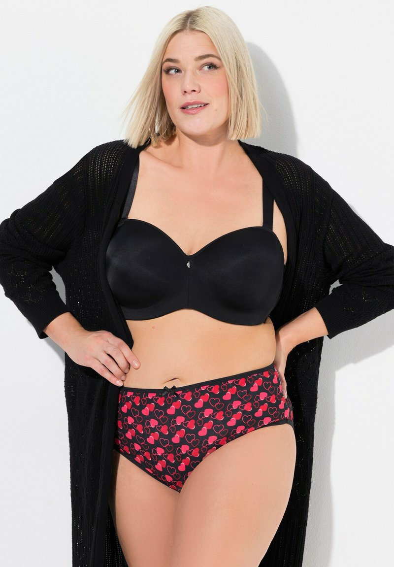 Reggiseno imbottito nero in tessuto liscio con spalline regolabili, abbinato a mutandine a vita alta con un motivo a cuori rossi su sfondo nero.