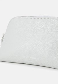 Light grey leather pouch with a pebbled texture, a zip closure, and a silver logo on the front. Rounded shape, smooth stitching detail.