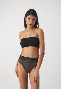 Must zwart strapless top, milleeritud esiosa; läbipaistvad kõrge vöökohtadega alumised osad tekstuuriga vööga ja siledast mustast kangast.