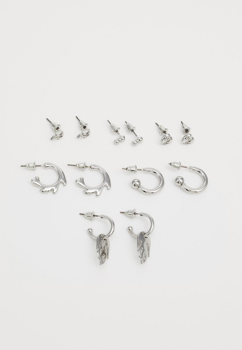 Conjunto de pendientes de plata que presenta aros retorcidos, diseños de tuerca y acentos de llama distintivos; se incluyen varias formas y tamaños.
