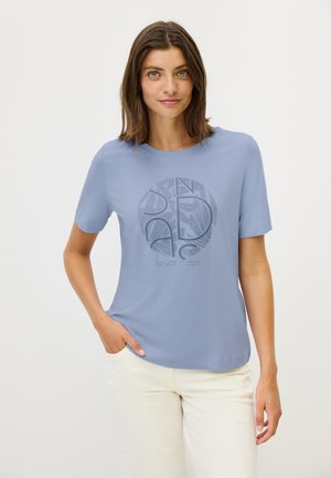 Camiseta de manga corta azul claro con un diseño gráfico redondo en azul oscuro y texto. Tela suave y corte relajado.