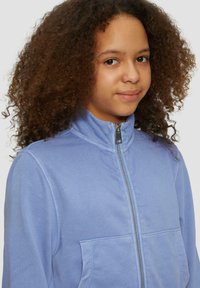 Helles blaues Zip-Jacke mit Stehkragen, ausgestattet mit einer Vorderatetasche und einem weichen, glatten Stoffgefühlt.