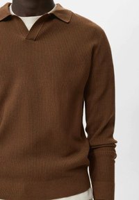 Suéter marrón de punto acanalado con cuello tipo polo, mangas largas y tejido texturizado. Presenta un escote en v y detalles de dobladillo ajustado.
