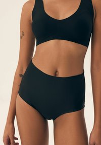 Black sports bra and high-waisted briefs made of smooth fabric, featuring simple, seamless design with no visible hardware or patterns.