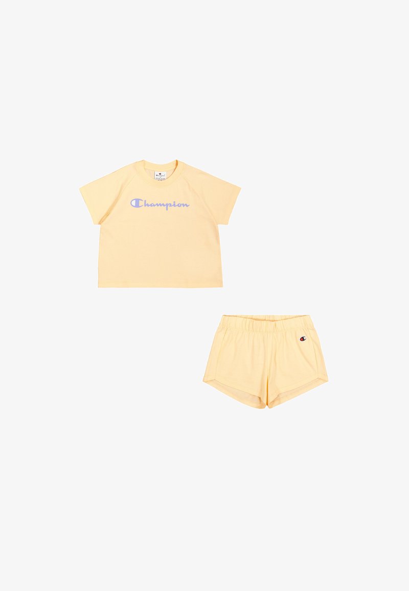 Camiseta de algodón amarilla con el logo azul de "Champion" y pantalones cortos a juego con cintura elástica y parche de logo. Diseño simple, con mangas cortas.