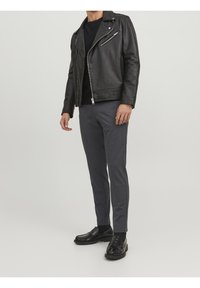 Svart läderbikerjacka med flera dragkedjefickor, figursydda grå byxor och svarta loafers. Slät yta, skräddarsydd passform och klassisk design.