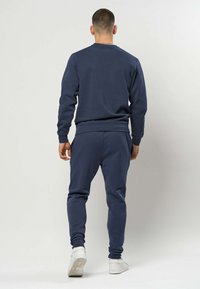 Marineblå genser og joggebukse sett laget av mykt stoff, med ribbestrikket rund hals og mansjetter, og en slank passform.