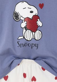 Cotton t-shirt in lavender featuring a glittery red heart held by Snoopy. Below, white shorts with scattered red heart patterns.