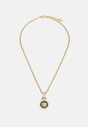 Gold chain necklace with a round pendant featuring a lion head design on a black background and engraved brand name around the edge.