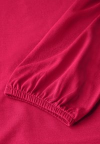 Fuchsia Langarmshirt mit gerafften Bündchen. Glattes, dehnbares Material mit einem subtilen Glanz und einem schlichten Design. Leicht und figurbetont.