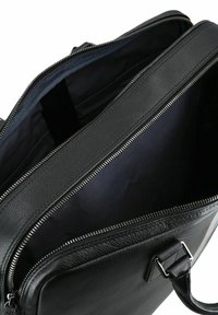 Zwarte leren tas met een gestructureerde buitenkant, dubbele ritssluitingen en een ruime, donkere binnenvoering van soepel stof.