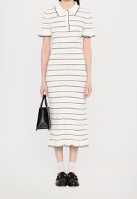 Robe midi à rayures blanches avec des manches courtes et un col polo. Présente des rayures verticales noires, une texture côtelée et un ourlet évasé.