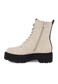 Stivaletti alla caviglia in finta suede beige con una suola platform nera spessa. Le caratteristiche includono lacci frontali e una cerniera laterale.