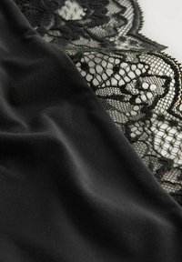 Tessuto nero con una texture liscia accanto a pizzo nero intricato, che mette in mostra un motivo floreale e un bordo ondulato per dettagli e contrasto.