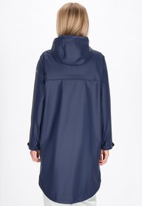 Chaqueta con capucha impermeable en color marino, de manga larga, con puños elásticos y dobladillo curvado. Textura suave, diseño minimalista, sin patrones visibles.