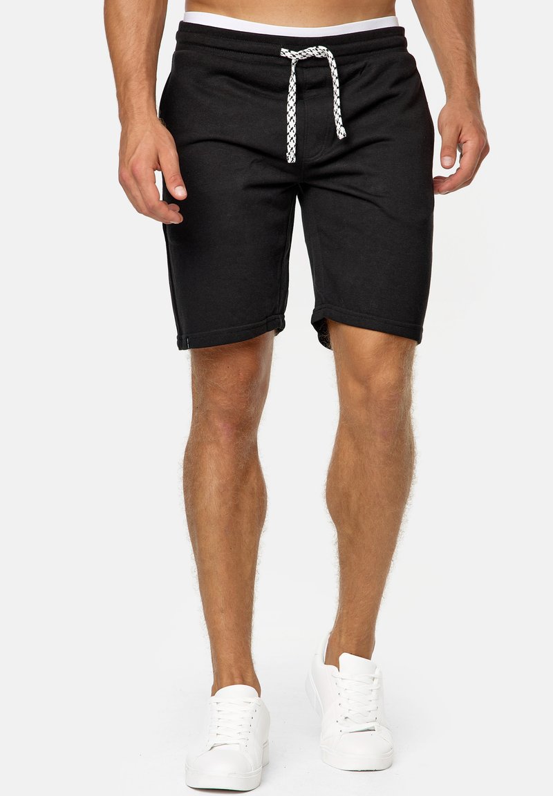 Shorts noirs en coton avec une taille élastique et un cordon blanc, présentant un design décontracté et une longueur au-dessus du genou.