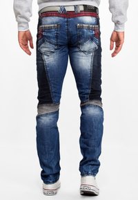 Denim jeans in verschillende blauwtinten met gecreëerde plekken. Bevat zakken, stiksels en een recht model. Aangevuld met een grijze tailleband.
