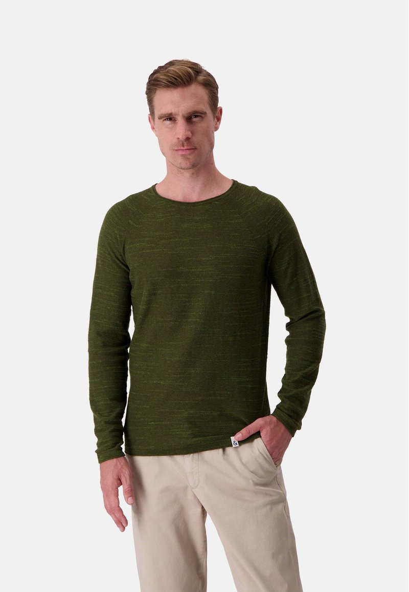 Dunkelgrüner Langarm-Crewneck-Pullover mit subtiler Textur, gerippten Bündchen und einem kleinen Logotag am Saum, kombiniert mit beigen Hosen.