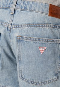 Ανοιχτό μπλε τζιν παντελόνι με ξεθωριασμένη υφή, διαθέτει τριγωνική κόκκινη και λευκή ετικέτα στο πίσω τσέπη. Κλασικός σχεδιασμός 5 τσεπών.