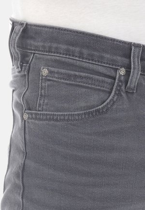 Jean de mezclilla gris con diseño de cinco bolsillos, herrajes plateados y un ajuste slim. La tela tiene una textura suave con ligeros desvanecimientos.